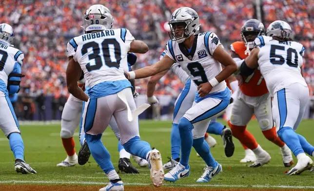 Carolina Panthers quarterback Bryce Young (9) hands the ball off to running back Chuba Hubbard (30) during the first half of an NFL football game against the Denver Broncos, Sunday, Oct. 27, 2024, in Denver. (AP Photo/Jack Dempsey)