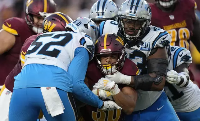 Washington Commanders running back Austin Ekeler (30) is tackled by Carolina Panthers linebacker DJ Johnson (52) and defensive end LaBryan Ray (93) during the second half of an NFL football game, Sunday, Oct. 20, 2024, in Landover, Md. (AP Photo/Stephanie Scarbrough)