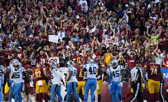 Washington Commanders fans celebrate after a touchdown run by Commanders running back Brian Robinson Jr. during the first half of an NFL football game against the Carolina Panthers, Sunday, Oct. 20, 2024, in Landover, Md. (AP Photo/Stephanie Scarbrough)