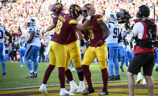 Washington Commanders running back Brian Robinson Jr. (8) celebrates with teammate quarterback Marcus Mariota (18) after an 8-yard touchdown run during the first half of an NFL football game against the Carolina Panthers, Sunday, Oct. 20, 2024, in Landover, Md. (AP Photo/Nick Wass)