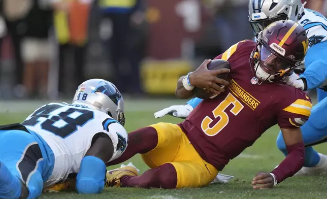 Washington Commanders quarterback Jayden Daniels (5) is tackled by Carolina Panthers linebacker Thomas Incoom (48) during the first half of an NFL football game, Sunday, Oct. 20, 2024, in Landover, Md. (AP Photo/Stephanie Scarbrough)