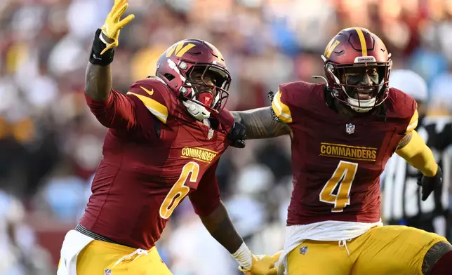 Washington Commanders linebacker Dante Fowler Jr. (6) and linebacker Frankie Luvu (4) celebrate after stopping the Carolina Panthers on fourth down during the first half of an NFL football game, Sunday, Oct. 20, 2024, in Landover, Md. (AP Photo/Nick Wass)