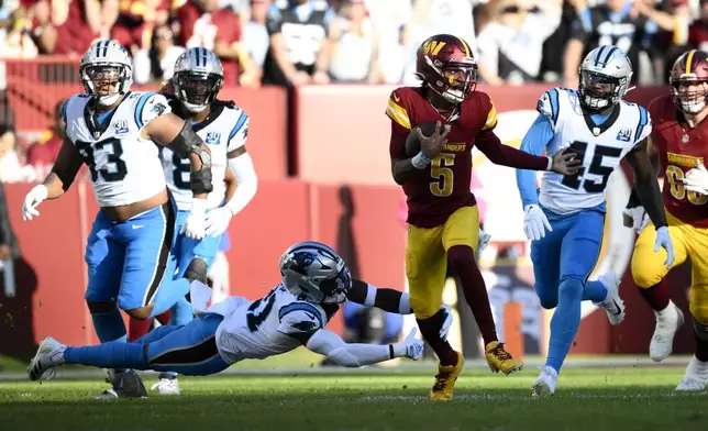 Washington Commanders quarterback Jayden Daniels (5) runs from Carolina Panthers safety Nick Scott (21) and linebacker Marquis Haynes Sr. (45) during the first half of an NFL football game, Sunday, Oct. 20, 2024, in Landover, Md. (AP Photo/Nick Wass)