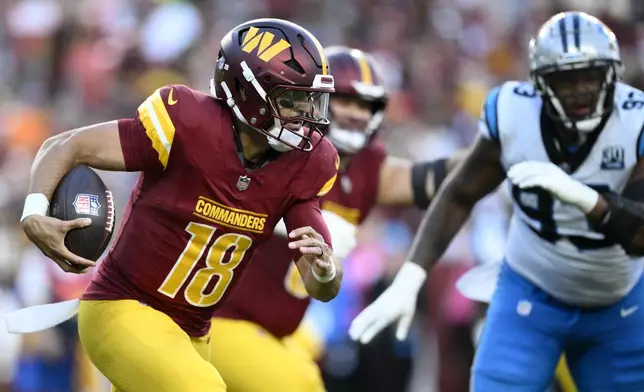 Washington Commanders quarterback Marcus Mariota (18) runs from Carolina Panthers defensive end LaBryan Ray (93) during the first half of an NFL football game, Sunday, Oct. 20, 2024, in Landover, Md. (AP Photo/Nick Wass)