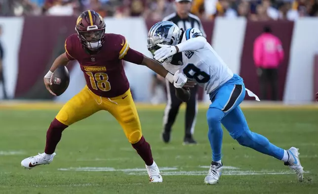 Washington Commanders quarterback Marcus Mariota (18) runs from Carolina Panthers cornerback Jaycee Horn (8) during the first half of an NFL football game, Sunday, Oct. 20, 2024, in Landover, Md. (AP Photo/Stephanie Scarbrough)