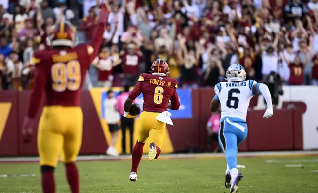 Washington Commanders linebacker Dante Fowler Jr. runs from Carolina Panthers running back Miles Sanders, right, as he returns an interception 67 yards for a touchdown during the first half of an NFL football game, Sunday, Oct. 20, 2024, in Landover, Md. (AP Photo/Nick Wass)