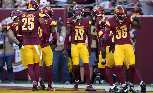 Washington Commanders cornerback Emmanuel Forbes Jr. (13) celebrates with teammates after intercepting a pass during the first half of an NFL football game against the Carolina Panthers, Sunday, Oct. 20, 2024, in Landover, Md. (AP Photo/Stephanie Scarbrough)