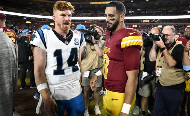 Carolina Panthers quarterback Andy Dalton (14) talks Washington Commanders quarterback Marcus Mariota (18) after an NFL football game, Sunday, Oct. 20, 2024, in Landover, Md. The Commanders 40-7. (AP Photo/Nick Wass)