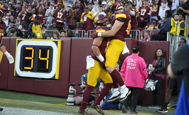 Washington Commanders tight end Ben Sinnott, right, celebrates after catching a 3-yard touchdown pass during the second half of an NFL football game against the Carolina Panthers, Sunday, Oct. 20, 2024, in Landover, Md. (AP Photo/Stephanie Scarbrough)