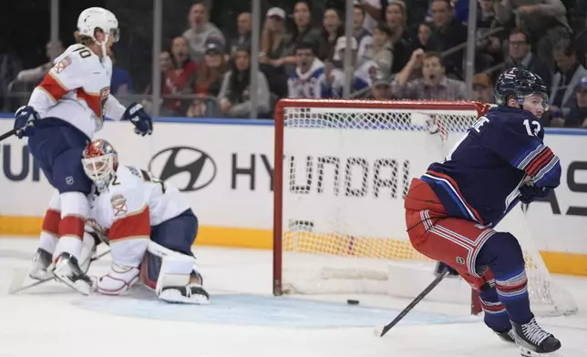 New York Rangers' Alexis Lafrenière (13) looks away from Florida Panthers goaltender Sergei Bobrovsky (72) and A.J. Greer (10) after scoring during the first period of an NHL hockey game Thursday, Oct. 24, 2024, in New York. (AP Photo/Frank Franklin II)