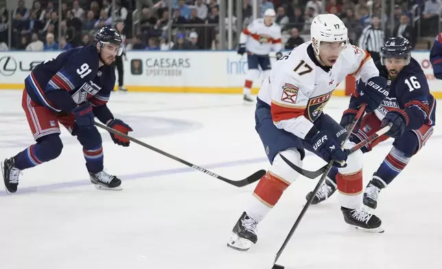 Florida Panthers' Evan Rodrigues (17) drives past New York Rangers' Vincent Trocheck (16) and Reilly Smith (91) during the second period of an NHL hockey game Thursday, Oct. 24, 2024, in New York. (AP Photo/Frank Franklin II)