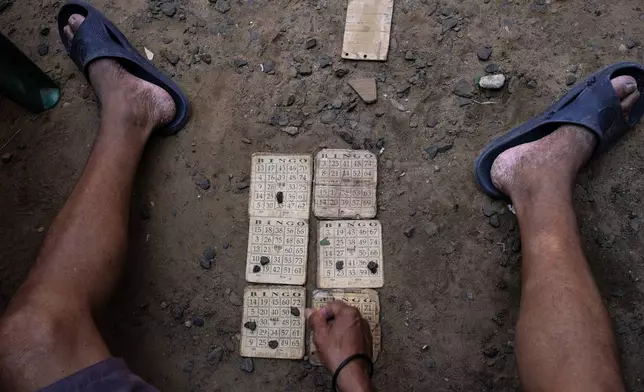 A prisoner uses pebbles to mark his bingo card in the prison yard of the Regional Penitentiary in Villarica, Paraguay, Friday, Aug. 30, 2024. Prisoners pay per bingo card and the winner takes all. (AP Photo/Rodrigo Abd)