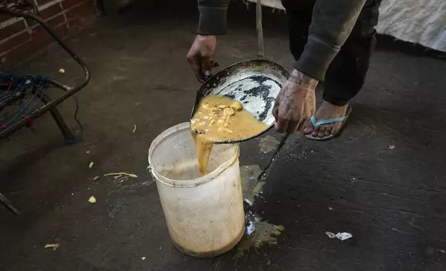 A prisoner divides up jail-provided soup known as "vori vori" at the Tacumbu prison in Asuncion, Paraguay, Wednesday, July 10, 2024. The soup, made of chicken or beef, vegetables, and corn balls stuffed with cheese, is considered the food of the poorest inmates, and those who can afford it prefer to buy other food. (AP Photo/Rodrigo Abd)