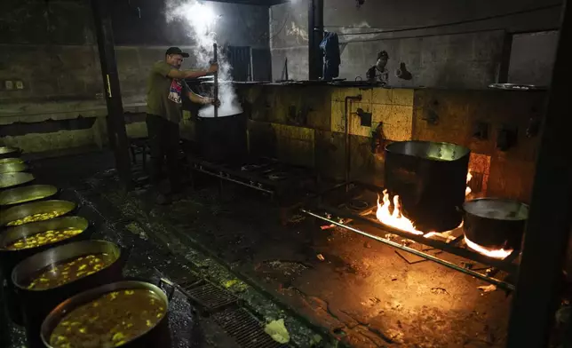 A prisoner cooks a vegetable, cheese and bean stew to serve at the Tacumbu prison in Asuncion, Paraguay, Sunday, July 8, 2024. (AP Photo/Rodrigo Abd)