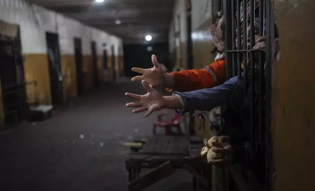 Prisoners reach out from their cell for bread at lunchtime at the Juan de la Vega prison in Emboscada, Paraguay, Friday, July 12, 2024. (AP Photo/Rodrigo Abd)