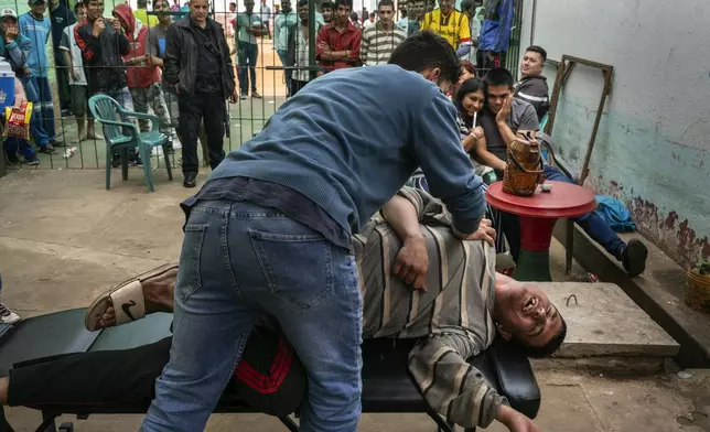 A prisoner gives a free stretching session to a volunteer during events on visiting day at the Regional Penitentiary in Villarica, Paraguay, Sunday, Sept. 1, 2024. (AP Photo/Rodrigo Abd)