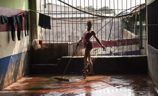 Magali Vargas, 29, strikes a pose while cleaning the floor of the pavilion reserved for transgender inmates at the Regional Penitentiary in Coronel Oviedo, Paraguay, Friday, Aug. 30, 2024. (AP Photo/Rodrigo Abd)