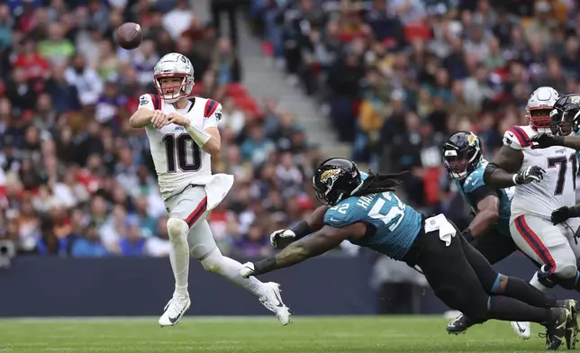 New England Patriots quarterback Drake Maye (10) is pressured by Jacksonville Jaguars defensive tackle DaVon Hamilton (52) during the first half of an NFL football game, Sunday, Oct. 20, 2024, in London. (AP Photo/Ian Walton)