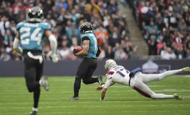 Jacksonville Jaguars' Parker Washington breaks from New England Patriots punter Bryce Baringer (17) to score on a 96-yard punt return during the first half of an NFL football game, Sunday, Oct. 20, 2024, in London. (AP Photo/Kin Cheung)