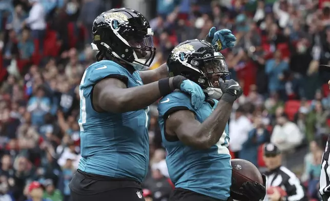 Jacksonville Jaguars running back Tank Bigsby, right, celebrates his 1-yard rushing touchdown during the first half of an NFL football game against the New England Patriots, Sunday, Oct. 20, 2024, in London. (AP Photo/Ian Walton)