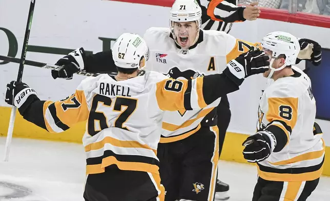 Pittsburgh Penguins' Rickard Rakell (67) celebrates with teammates Evgeni Malkin (71) and Michael Bunting (8) after scoring against the Montreal Canadiens during the first period of an NHL hockey game in Montreal, Monday, Oct. 14, 2024. (Graham Hughes/The Canadian Press via AP)