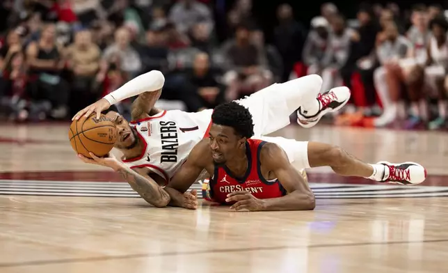 Portland Trail Blazers guard Anfernee Simons, left, dives for the ball against New Orleans Pelicans forward Herbert Jones, right, during the second half of an NBA basketball game Sunday, Oct. 27, 2024, in Portland, Ore. (AP Photo/Howard Lao)