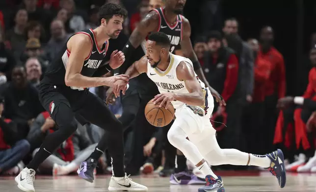 New Orleans Pelicans guard CJ McCollum, right, drives to the basket as Portland Trail Blazers forward Deni Avdija, left, defends during the first half of an NBA basketball game Friday, Oct. 25, 2024, in Portland, Ore. (AP Photo/Amanda Loman)