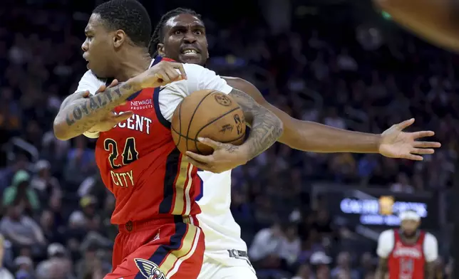 New Orleans Pelicans guard Jordan Hawkins (24) is defend by Golden State Warriors forward Kevon Looney, back, during the first half of an NBA basketball game in San Francisco, Tuesday, Oct. 29, 2024. (AP Photo/Jed Jacobsohn)