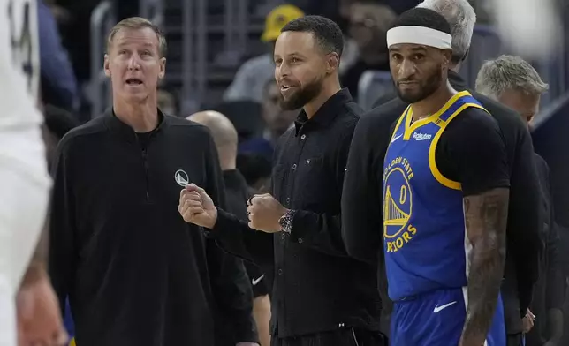 Golden State Warriors assistant coach Terry Stotts, left, stands next to injured guard Stephen Curry, middle, and guard Gary Payton II (0) during a timeout in the first half of an NBA basketball game against the New Orleans Pelicans in San Francisco, Wednesday, Oct. 30, 2024. (AP Photo/Jeff Chiu)