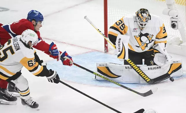 Montreal Canadiens' Juraj Slafkovsky (20) moves in on Pittsburgh Penguins goaltender Tristan Jarry as Penguins' Erik Karlsson (65) defends during the second period of a NHL hockey game against the Pittsburgh Penguins in Montreal, Monday, Oct. 14, 2024. (Graham Hughes/The Canadian Press via AP)