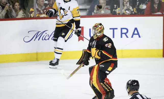 Calgary Flames goalie Dustin Wolf celebrates as Pittsburgh Penguins' Evgeni Malkin looks on after an NHL hockey game on Tuesday, Oct. 22, 2024 in Calgary, Alberta. (Jeff McIntosh/The Canadian Press via AP)