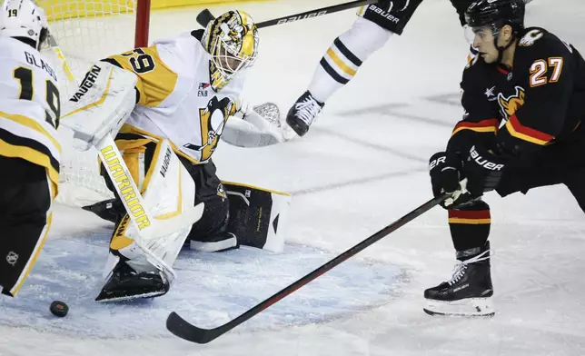 Pittsburgh Penguins goalie Alex Nedeljkovic kicks the puck away from Calgary Flames' Matthew Coronato during the first period of an NHL hockey game on Tuesday, Oct. 22, 2024 in Calgary, Alberta. (Jeff McIntosh/The Canadian Press via AP)