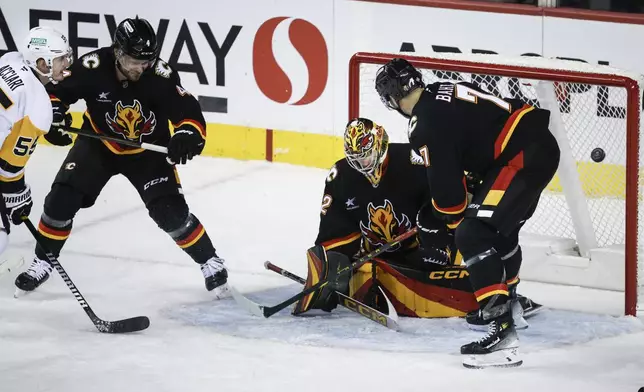 Pittsburgh Penguins' Noel Acciari, left, scores on Calgary Flames goalie Dustin Wolf, center, during the third period of an NHL hockey game on Tuesday, Oct. 22, 2024 in Calgary, Alberta. (Jeff McIntosh/The Canadian Press via AP)