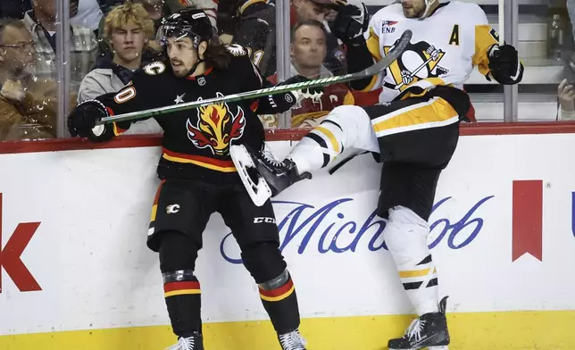 Pittsburgh Penguins' Kris Letang, right, is checked by Calgary Flames' Ryan Lomberg during the second period of an NHL hockey game on Tuesday, Oct. 22, 2024 in Calgary, Alberta. (Jeff McIntosh/The Canadian Press via AP)