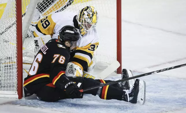 Pittsburgh Penguins goalie Alex Nedeljkovic, right, pushes Calgary Flames' Martin Pospisil away after he crashed into the net during the first period of an NHL hockey game on Tuesday, Oct. 22, 2024 in Calgary, Alberta. (Jeff McIntosh/The Canadian Press via AP)