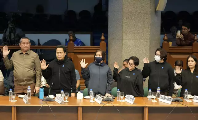 Apollo Quiboloy, second from left, a Filipino preacher accused of sexual abuse and human trafficking in the Philippines and similar charges in the United States, takes oath before a senate inquiry at the Philippine Senate Wednesday, Oct. 23, 2024, in Manila, Philippines. (AP Photo/Aaron Favila)