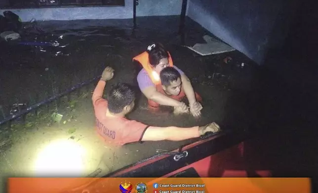 In this photo provided by the Philippine Coast Guard, rescuers carry a resident to safer grounds as they navigate floods caused by Tropical Storm Trami in Guinobatan, Albay province, Philippines Tuesday Oct. 22, 2024. (Philippine Coast Guard via AP)