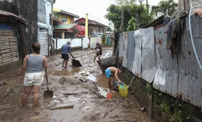 Residents collect mud as they start cleaning their area after floods caused by Tropical Trami, locally named Kristine, hit in Polangui, Albay province, Philippines on Oct. 23, 2024. (AP Photo/John Michael Magdasoc)