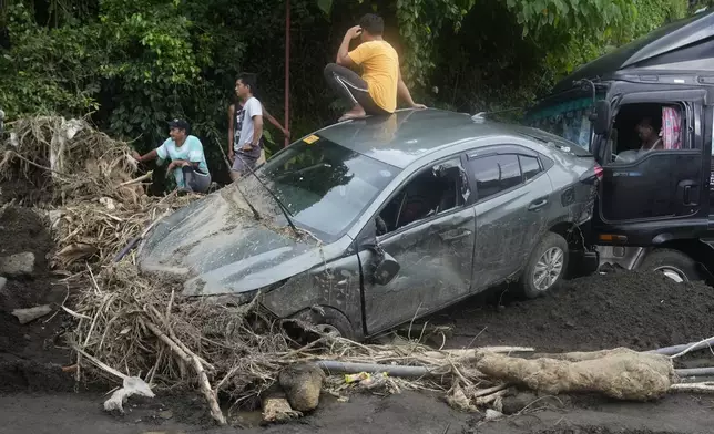 A man sits on a damaged car after a landslide triggered by Tropical Storm Trami in Talisay, Batangas province, Philippines, Saturday, Oct. 26, 2024. (AP Photo/Aaron Favila)