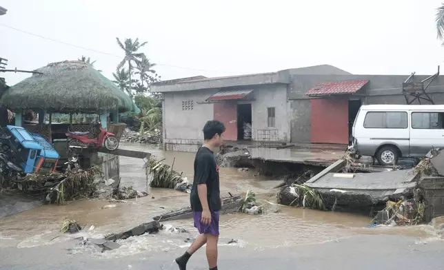 A man walks past damages caused by flash floods on Thursday Oct. 24, 2024 after Tropical Storm Trami, locally named Kristine, dumped heavy rains at Libon town, Albay province, Philippines. (AP Photo/John Michael Magdasoc)