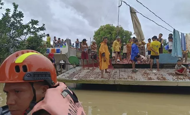 In this photo provided by the Philippine Coast Guard, residents wait on top of their roofs to avoid floods caused by Tropical Storm Trami in Libon, Albay province, Philippines on Wednesday Oct. 23, 2024. (Philippine Coast Guard via AP)