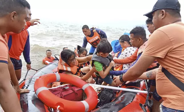 In this photo provided by the Philippine Coast Guard, residents alight a rubber boat after being ferried to safer grounds in Batangas province, Philippines on Friday, Oct. 25, 2024. (Philippine Coast Guard via AP)