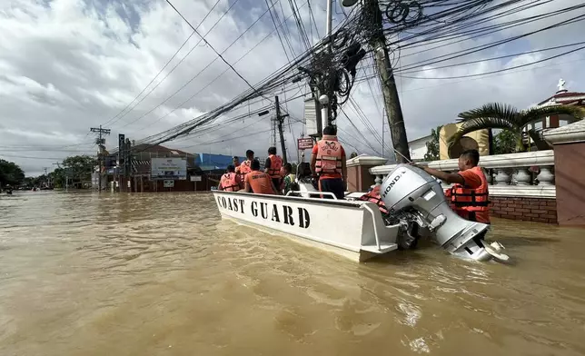 In this photo provided by the Philippine Coast Guard, rescuers ride a boat around the flooded town of Nabua, Camarines Sur, Philippines on Friday Oct. 25, 2024. (Philippine Coast Guard via AP)