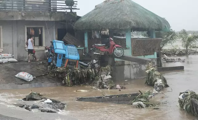 A man walks past damages caused by flash floods on Thursday Oct. 24, 2024 after Tropical Storm Trami, locally named Kristine, dumped heavy rains at Libon town, Albay province, Philippines. (AP Photo/John Michael Magdasoc)