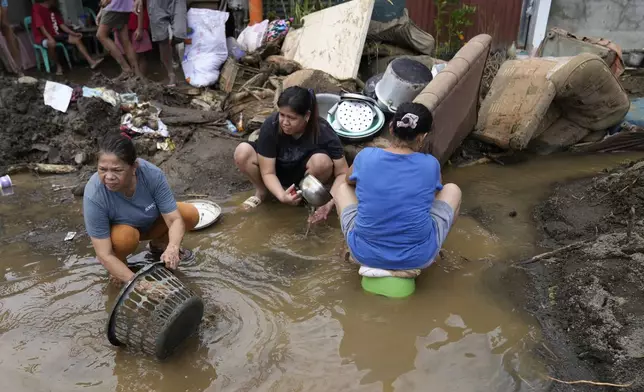 Residents try to clear out mud from their belongings after a landslide triggered by Tropical Storm Trami recently struck Talisay, Batangas province, Philippines, Saturday, Oct. 26, 2024. (AP Photo/Aaron Favila)