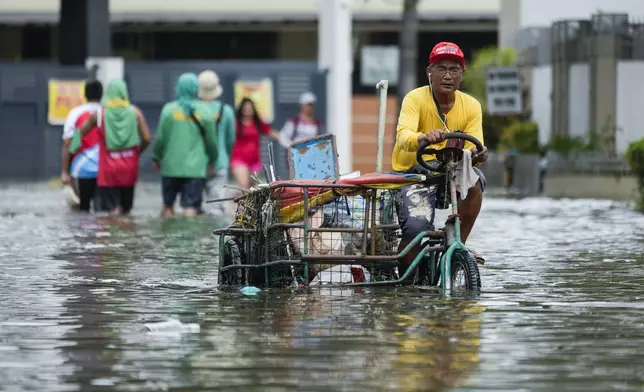 A man navigates flooded streets caused by Tropical Storm Trami on Friday, Oct. 25, 2024, in Cainta, Rizal province, Philippines. (AP Photo/Aaron Favila)