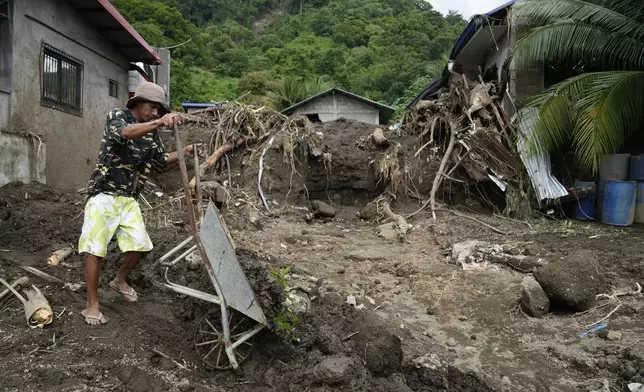 A resident cleans out mud from his damaged home as it was struck by a landslide triggered by Tropical Storm Trami on Saturday, Oct. 26, 2024, in Talisay, Batangas province, Philippines. (AP Photo/Aaron Favila)