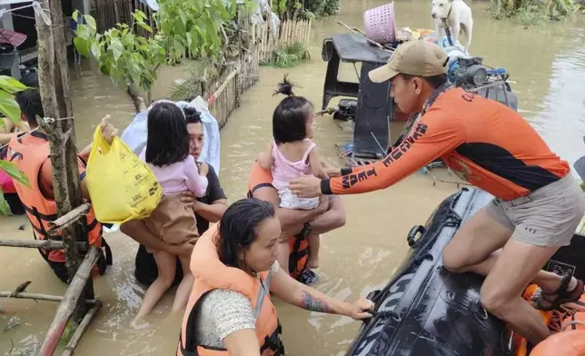 In this handout photo provided by the Philippine Coast Guard, rescuers carry residents trapped in their home after floods caused by Tropical Storm Trami, locally named Kristine, hit their village at Libon, Albay province, Philippines on Wednesday, Oct. 23, 2024. (Philippine Coast Guard via AP)