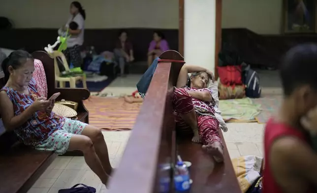 Evacuees lie on pews inside the Holy Family Parish that is used as a temporary evacuation center after floods caused by Tropical Storm Trami, locally named Kristine, inundate their village on Thursday, Oct. 24, 2024, in Quezon city, Philippines. (AP Photo/Aaron Favila)