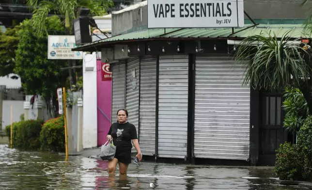 A resident crosses flooded streets caused by Tropical Storm Trami on Friday, Oct. 25, 2024, in Cainta, Rizal province, Philippines. (AP Photo/Aaron Favila)